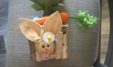 Easter table centerpiece with carrot, bunny face, eggs and wood bark on a glass square bowl