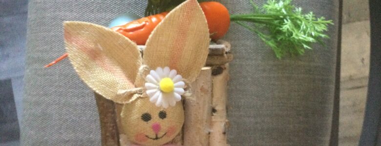 Easter table centerpiece with carrot, bunny face, eggs and wood bark on a glass square bowl