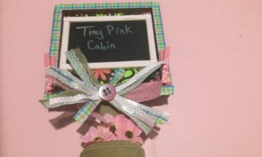 chalkboard sign on wood stand with ribbon and flowers