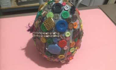 large ceramic egg with buttons and jewelry glued all over it