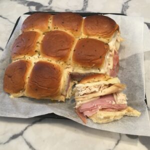 Hawaiian rolls with chicken, ham, swiss and sauce baked in oven