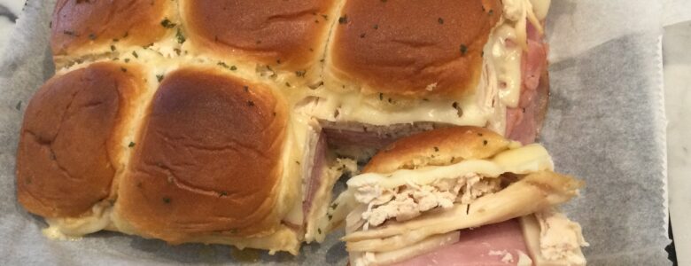 Hawaiian rolls with chicken, ham, swiss and sauce baked in oven